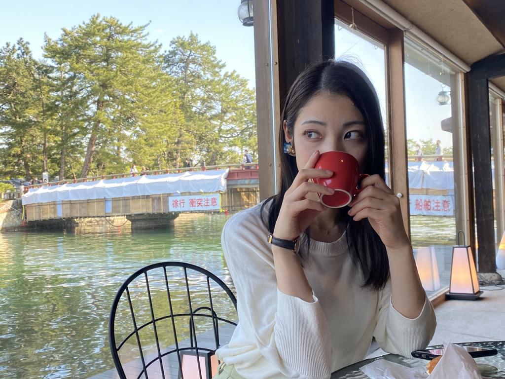 A woman drinking out of a cup while looking at the ocean